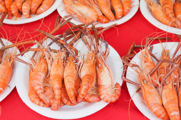  steamed shrimps in white paper dish on red table background