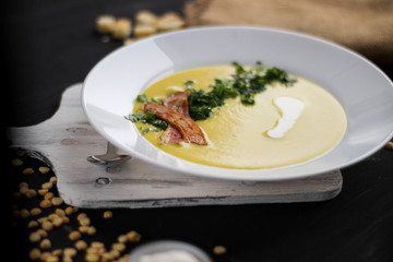 Pea soup with pieces of bacon, parsley and onion in a bowl on a dark background. Pea cream soup. macro focus shading