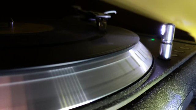 Closeup of a turntable spinning a record, while the grooves are lit under LED light.