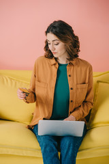 beautiful woman holding credit card while using laptop