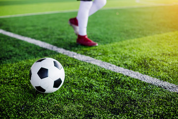 Obraz premium football on green artificial turf with soccer player speed run