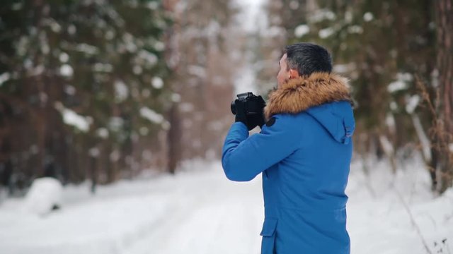 Man taking pictures in winter forest. Slowmoyotion