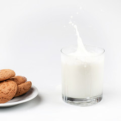 A glass of milk and oatmeal cookies on a light background. Healthy breakfast. Milk spray