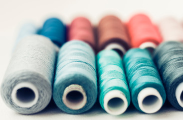 Colored sewing thread coils on white background with copy space for text.