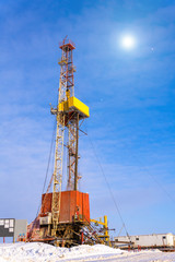 Oil and Gas Drilling Rig onshore dessert with dramatic cloudscape. Oil drilling rig operation on the oil platform in oil and gas industry. Land drilling rig blue sky