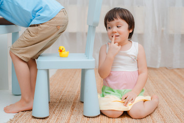 Sister puts a rubber duck on a chair under her brother's ass and hides on fool's day. Children's humor on April 1. Jokes and fun. Kids 3 years and 6 years