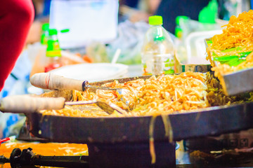 Close up hand of vendor during cooking for Padthai, the original Thai Fried Noodle, stir-fried noodle with shrimp and egg commonly served as a street food popular in Thailand