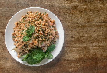 Thai cuisine spicy minced pork salad or Larb Moo dish on wood table background.