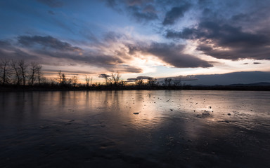 Sunset colors reflecting on the frozen surface of a pond