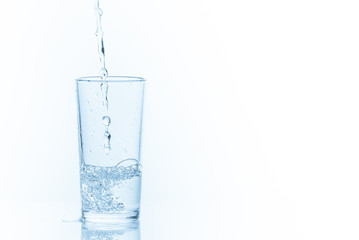 Pouring water into glass on white background. Photo with copy space.