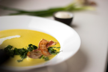 Pea soup with pieces of bacon, parsley and onion in a bowl on a white background macro. Pea cream soup.