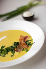 Pea soup with pieces of bacon, parsley and onion in a bowl on a white background macro. Pea cream soup.
