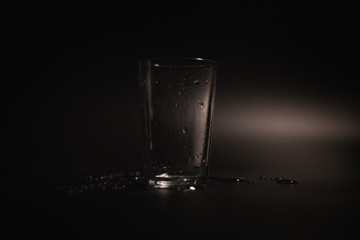 Water is poured into a transparent glass on a dark background
