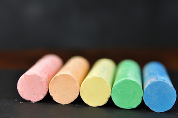School colored crayons on a dark background close-up. Study and education are conceptual. Color chalk