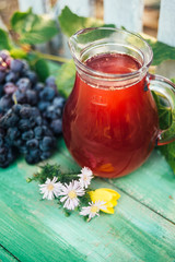 Carafe of red wine with a bunch of grapes and flowers