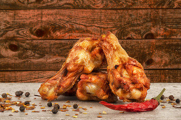 Chicken wings with red hot chili pepper, salt and peppercorn. Wooden plank in background. Copy space for your text.