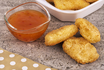 Chicken nuggets with sweet and sour sauce bowl disposed on a concrete background. Fast food concept.