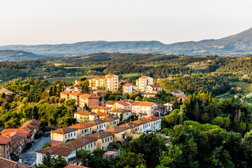 Fototapeta na wymiar Chiusi village cityscape at golden sunrise in Umbria Italy street road cars and rooftop houses on mountain countryside and rolling hills