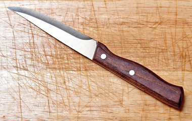 One steack knife on textured and scratched wooden plank