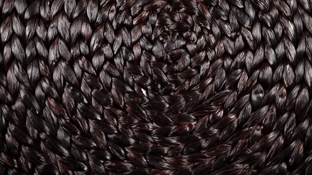 Dark brown wicker woven pattern rotating. Abstract background or texture. Top down view