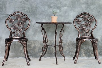 Brown table and chairs made from alloy on cement wall at coffee shop