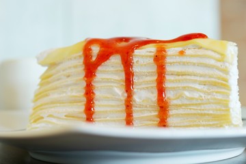 Close up, A Piece of crape cake with strawberry sauce on white ceramic plate
