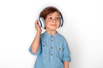 Boy in headphones studio standing isolated on grey listening music looking aside dreamful