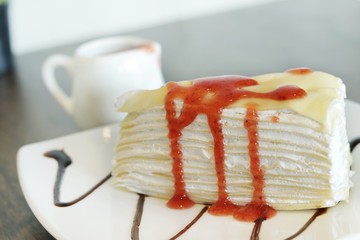 Close up, A Piece of crape cake with strawberry sauce on white ceramic plate for serving