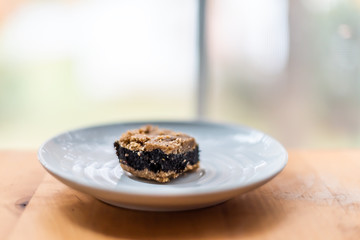 Closeup cut golden baked or raw poppy seed bar cake piece slice or chocolate bread filling on table white plate by window