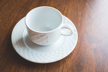 White mug for tea and saucer on wooden table.