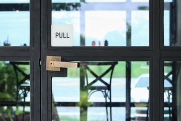 Pull sign engraved on the black metal and glass door with handle into the coffee shop, Loft style 