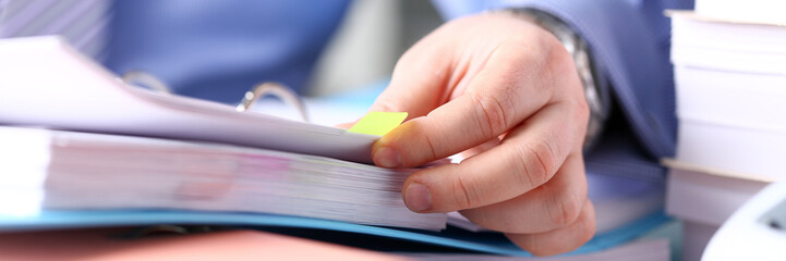 Clerk arm bend over pages in pile of bookmarked documents