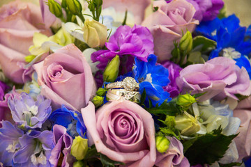 closeup of wedding rings among a bouquet  of colorful flowers and roses