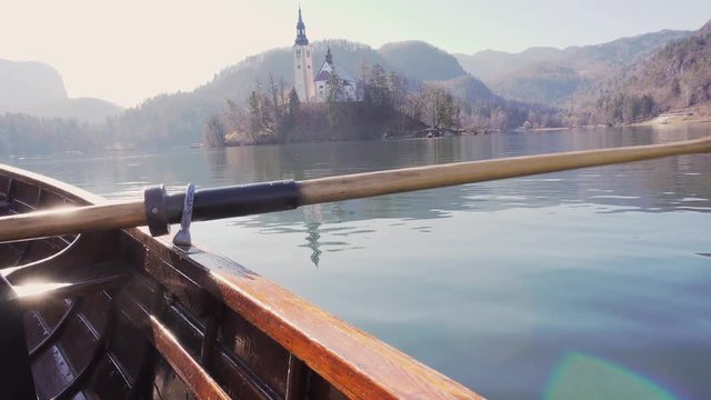 4K video - A paddle in the water on a sunny day - Rowing the boat with island Lake Bled in the background- Lake Bled, Slovenia