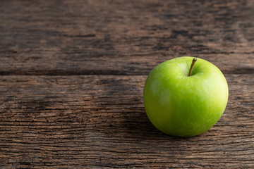 One green apple on wooden background.