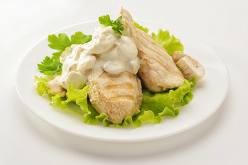 Fried chicken breast with cream sauce and mushrooms on a white plate. White background