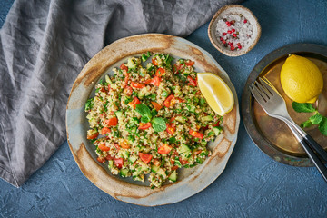 Tabbouleh salad with quinoa. Eastern food with vegetables mix on dark table, vegan diet. Top view