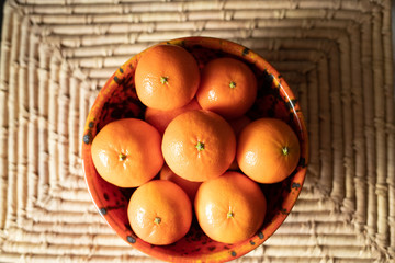 Mandarynki w pomarańczowej ceramicznej misce na słomkowek macie - obrazy, fototapety, plakaty