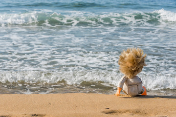 Fototapeta na wymiar Old Toy Doll Sitting on a Southern Italian Beach on a Sunny Day