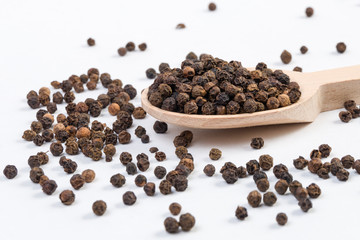 blask pepper peppercorns in wooden spoon isolated on white background. Closeup. © eyecon