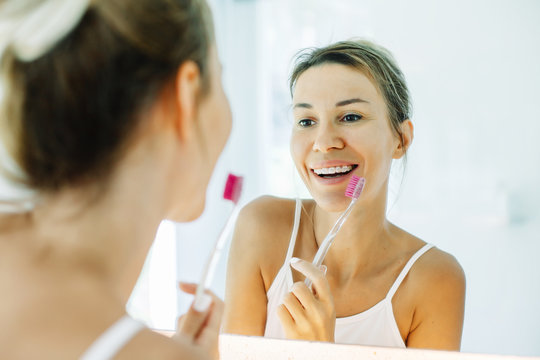 Woman brushing teeth in bathroom