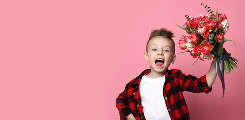 Little boy kid in white t-shirt and red shirt with a big bouquet of spring flowers congratulates happily with a holiday