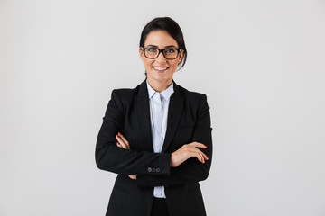 Portrait of successful businesswoman 30s in formal wear and eyeglasses standing in the office, isolated over white background