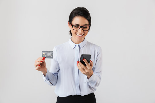 Image of young office woman wearing eyeglasses holding mobile phone and credit card, isolated over white background