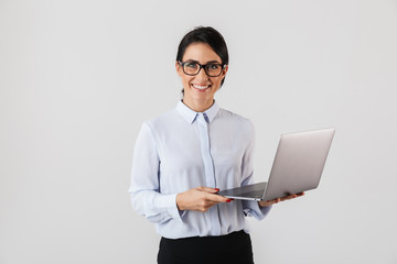 Portrait of young businesswoman wearing eyeglasses holding silver laptop in the office, isolated over white background - Powered by Adobe