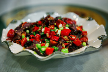 Traditional Chinese dish with slices of roast beef and red hot pepper, served on a white plate. Beijing, China.