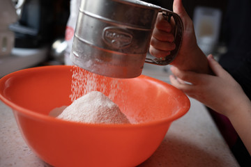 Przesiewanie mąki do pomarańczowej miski dłoń - obrazy, fototapety, plakaty