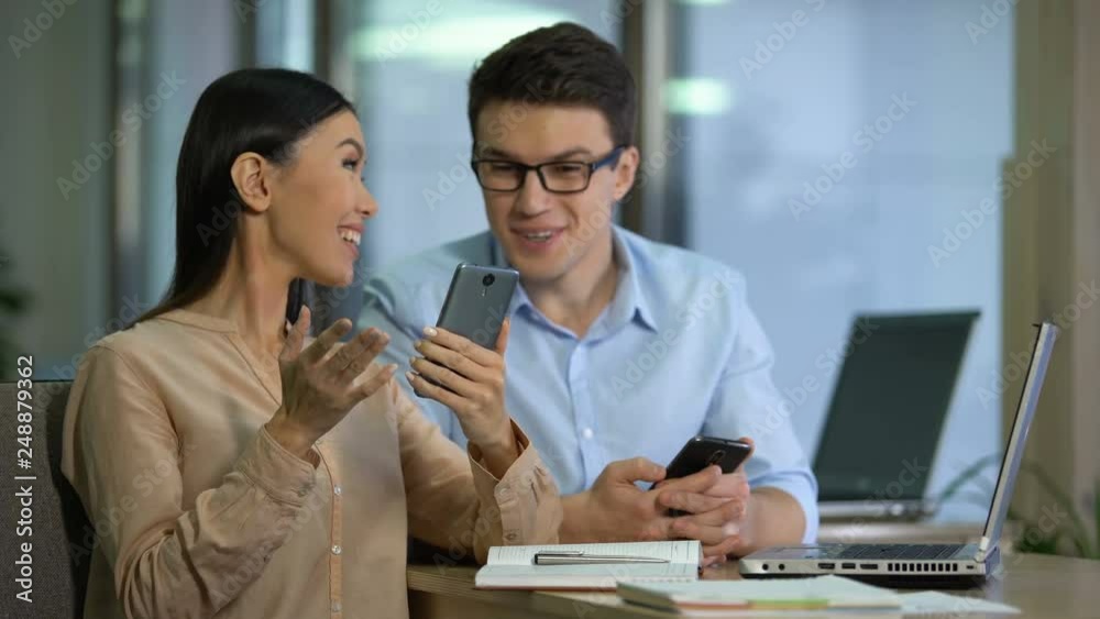 Wall mural two marketers testing work of new mobile app on smartphone, software engineering