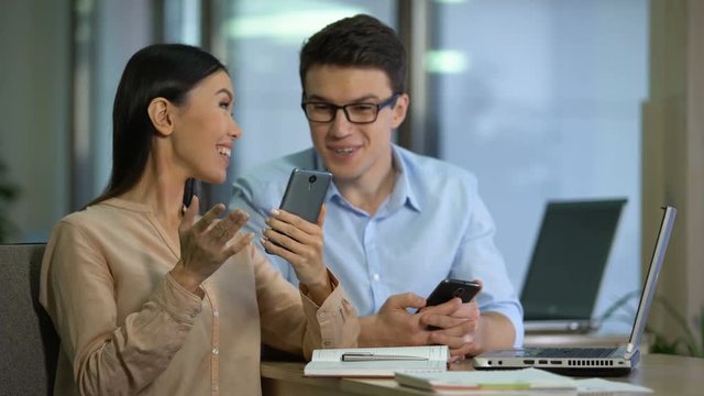 Two marketers testing work of new mobile app on smartphone, software engineering