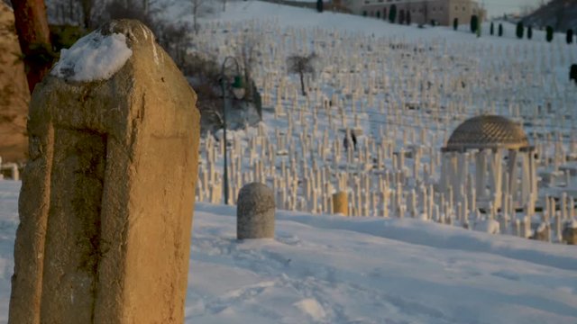 People walking around islamic cemetery Kovaci in Sarajevo during winter.